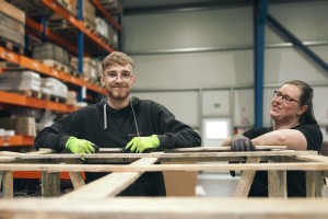 Eine weibliche und eine männliche Person stehen lächelnd in einem Warenlager.